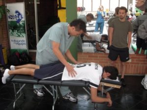 Dr. Lee adjusting tennis athlete at Colombia's Olympic Training Center